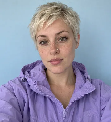 Original selfie of a woman with a platinum pixie cut in a lilac windbreaker